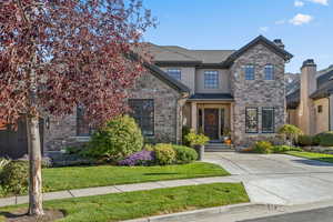 View of front facade with stone siding, a front lawn, and stucco siding