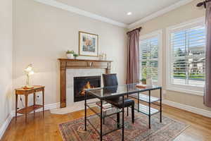Office area featuring crown molding, light wood finished floors, a fireplace, and recessed lighting