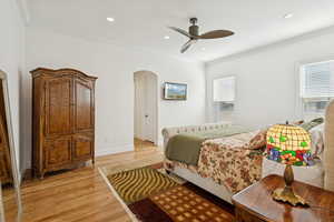 Master bedroom on main with ornamental molding, wood finished floors, crown molding, ceiling fan, and recessed lighting