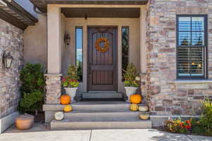Property entrance featuring stone siding, stucco siding, and a porch