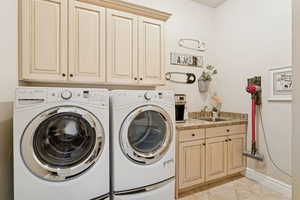 Laundry room on main level with washer and dryer, sink and cabinet space.