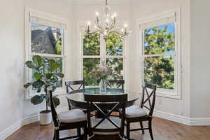 Dining space with wood finished floors, a chandelier, and ornamental molding