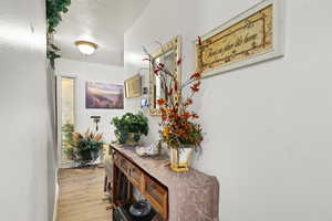 Hall featuring a textured ceiling and light wood finished floors