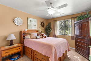 Bedroom with ceiling fan, a textured ceiling, and light colored carpet