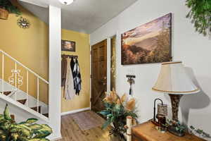 Foyer entrance with stairway, a textured ceiling, and wood finished floors