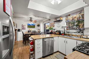 Kitchen with stainless steel appliances, a peninsula, a ceiling fan, white cabinetry, and a textured ceiling