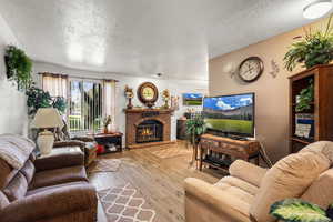Living room featuring a fireplace, light wood-style flooring, and a textured ceiling