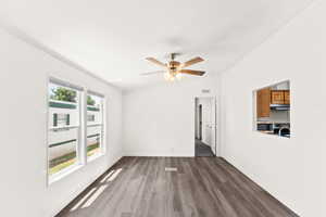 Unfurnished living room with dark wood-type flooring, ornamental molding, ceiling fan, and vaulted ceiling