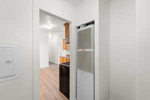 Hallway featuring a heating unit, light wood-style floors, and electric panel