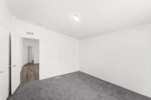 Carpeted spare room featuring lofted ceiling