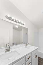 Full bathroom featuring double vanity, dark wood-style floors, and bathtub / shower combination