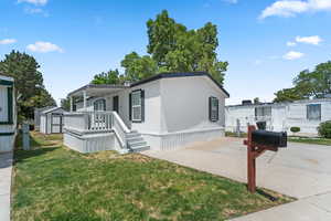 Manufactured / mobile home with a front yard, a storage shed, a patio area, and a deck