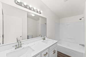 Full bathroom featuring tub / shower combination, double vanity, and dark wood finished floors