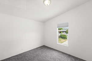 Carpeted spare room with lofted ceiling