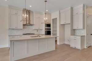 Kitchen featuring tasteful backsplash, decorative light fixtures, stainless steel appliances, light wood-style floors, and recessed lighting
