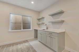 Bar area featuring open shelves, gray cabinetry, recessed lighting, light stone countertops, and light colored carpet