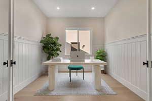 Office area featuring light wood-type flooring, a wainscoted wall, and recessed lighting