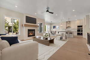 Living room featuring ceiling fan, a fireplace, recessed lighting, light wood-type flooring, and a chandelier
