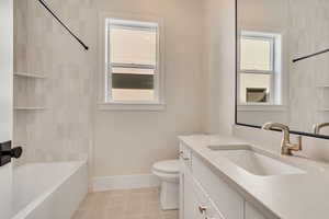 Bathroom with vanity, washtub / shower combination, and light tile patterned flooring