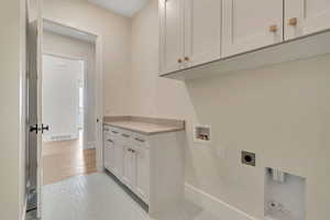 Laundry area with washer hookup, light tile patterned floors, electric dryer hookup, and cabinet space
