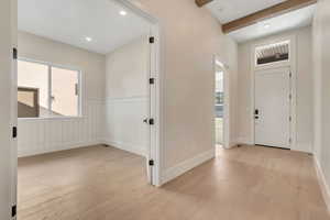 Entryway featuring light wood-type flooring, beam ceiling, recessed lighting, and a wainscoted wall