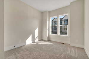 Unfurnished room featuring light colored carpet and baseboards