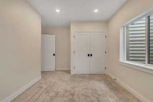 Unfurnished bedroom with light carpet, recessed lighting, and a closet
