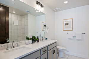 Bathroom featuring double vanity, recessed lighting, tiled shower, and light tile patterned floors