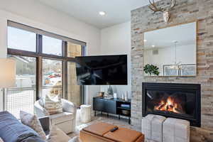 Living area featuring a stone fireplace, recessed lighting, wood finished floors, and a chandelier