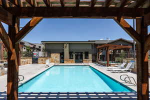 Community pool featuring a pergola, a hot tub, and a patio