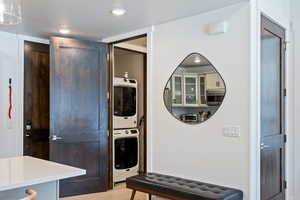 Laundry area with light wood finished floors, stacked washer and clothes dryer, and recessed lighting