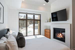 Bedroom with access to exterior, a glass covered fireplace, recessed lighting, and a ceiling fan