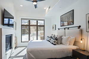 Carpeted bedroom with a glass covered fireplace, recessed lighting, and ceiling fan