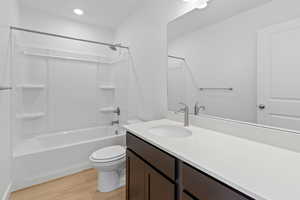 Bathroom with shower / tub combination, light wood-style floors, vanity, and recessed lighting