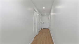 Hall with light wood-type flooring and recessed lighting
