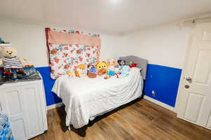 Bedroom with dark wood-style floors, washer / dryer, and ornamental molding