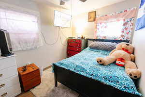 Bedroom featuring ceiling fan, multiple windows, and carpet