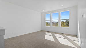 Empty room with light carpet and recessed lighting