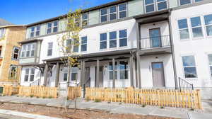 View of front of house featuring stucco siding, a balcony, and a fenced front yard