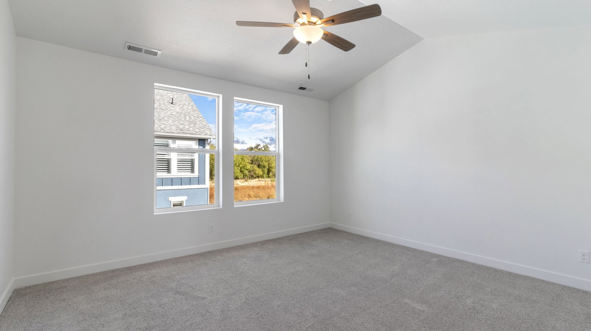 Unfurnished room with light colored carpet, vaulted ceiling, and ceiling fan