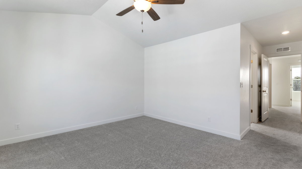 Spare room featuring carpet flooring, a ceiling fan, and vaulted ceiling