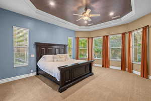 Bedroom with multiple windows, light colored carpet, crown molding, a raised ceiling, and recessed lighting