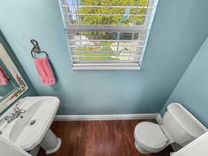 Half bath with baseboards and wood finished floors