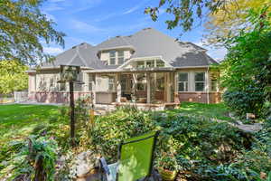 Back of property with brick siding, a shingled roof, a hot tub, and a patio area