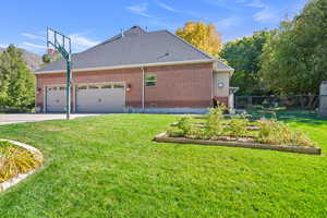 View of side of home featuring a garden, concrete driveway, a garage, brick siding, and roof with shingles