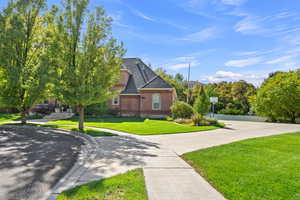 View of front of property featuring brick siding, a front yard, roof with shingles, and driveway