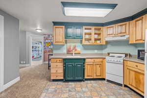 Kitchen with glass insert cabinets, white electric stove, light countertops, light colored carpet, and under cabinet range hood