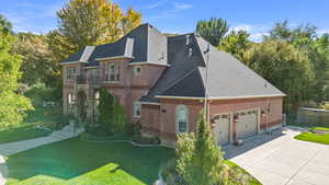 View of front of home with a shingled roof, brick siding, concrete driveway, and a garage