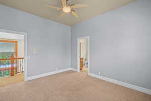 Carpeted spare room featuring baseboards and a ceiling fan