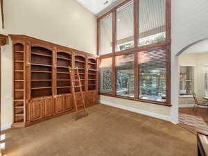 Unfurnished living room with a high ceiling, arched walkways, and light colored carpet